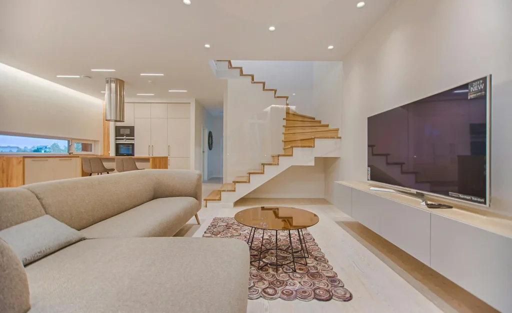 A stylish living room with a staircase and a television, highlighting modern decor and an open, inviting atmosphere.